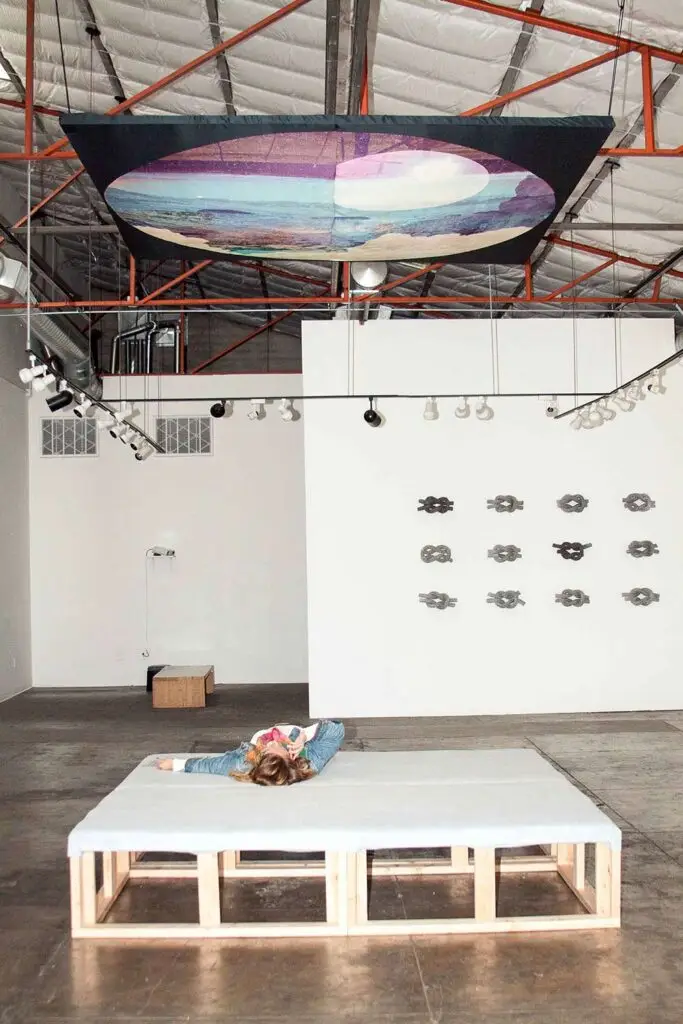 Installation art of a stargazing platform looking up to a custom tapestry created from photography and graphic design imagery.